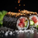 A close-up of a gourmet sushi roll with raw tuna, cucumber, sesame seeds, and soy sauce droplets