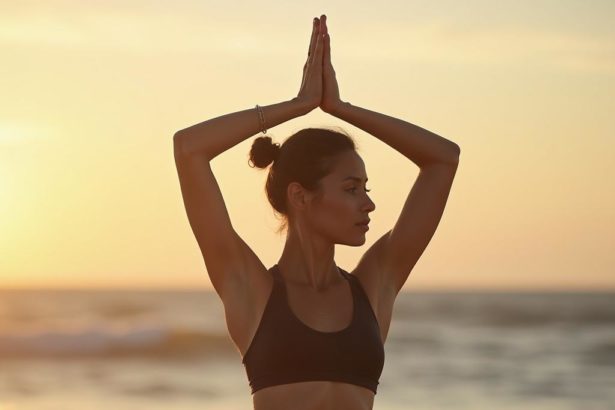 Portrait of a young athlete practicing yoga on a beach at sunrise with a blurry ocean backdrop.