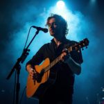 Portrait of a musician playing guitar on stage with spotlights, smoke, and dramatic lighting